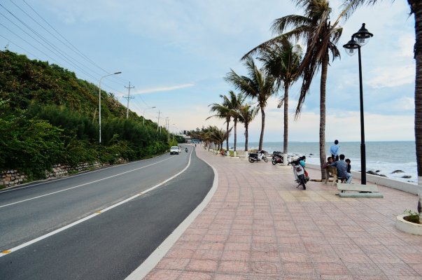 a road with a bit of a turn in it beside an ocean